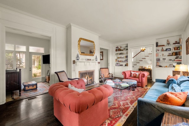 living room featuring built in shelves, crown molding, and dark hardwood / wood-style flooring