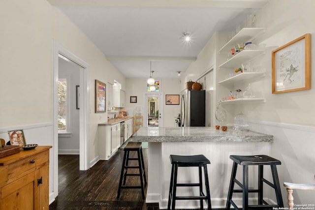 kitchen featuring light stone counters, kitchen peninsula, dark wood-type flooring, white cabinets, and appliances with stainless steel finishes