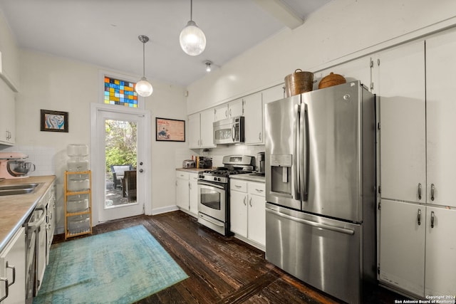 kitchen featuring dark wood-type flooring, backsplash, hanging light fixtures, white cabinetry, and appliances with stainless steel finishes