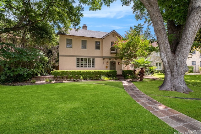 view of front of house with a balcony and a front lawn