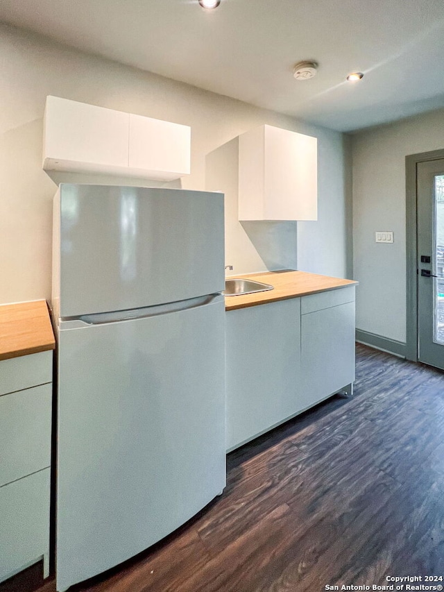 kitchen with white cabinetry, butcher block countertops, white refrigerator, and dark hardwood / wood-style flooring