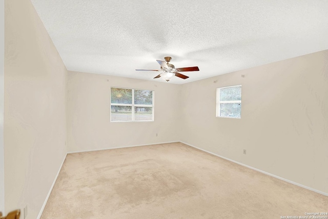 unfurnished room with light carpet, ceiling fan, a healthy amount of sunlight, and a textured ceiling