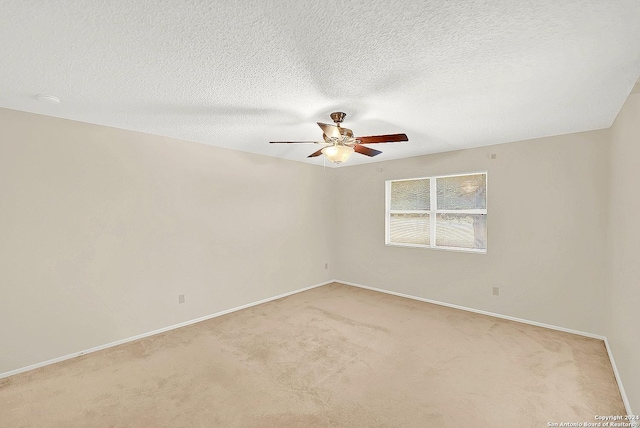 carpeted empty room with ceiling fan and a textured ceiling