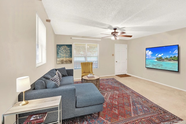 carpeted living room featuring ceiling fan and a textured ceiling