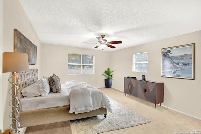 carpeted bedroom featuring ceiling fan and a textured ceiling