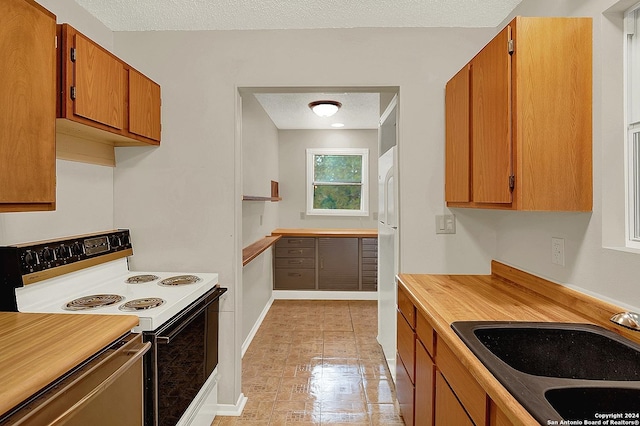 kitchen with sink, stainless steel dishwasher, a textured ceiling, electric stove, and light tile patterned flooring