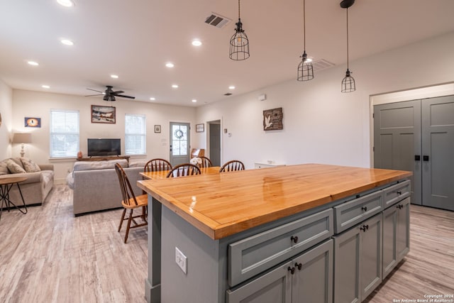 kitchen with pendant lighting, gray cabinetry, ceiling fan, a kitchen island, and butcher block counters