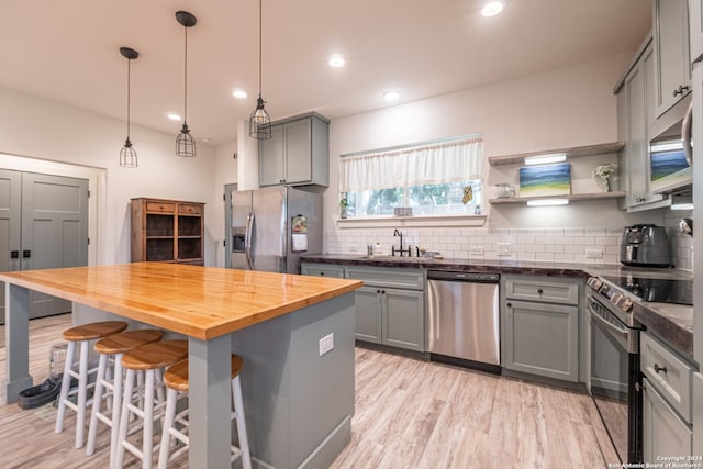 kitchen featuring wood counters, sink, gray cabinets, tasteful backsplash, and stainless steel appliances