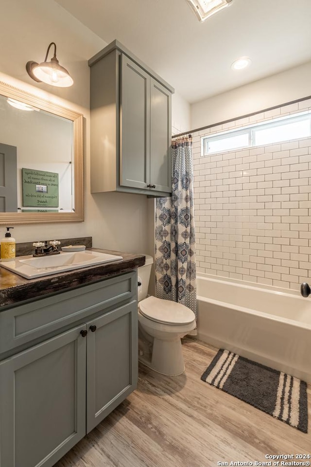 full bathroom featuring toilet, vanity, hardwood / wood-style flooring, and shower / tub combo with curtain