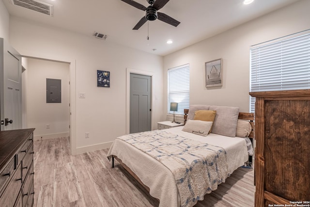 bedroom featuring ceiling fan, light wood-type flooring, and electric panel