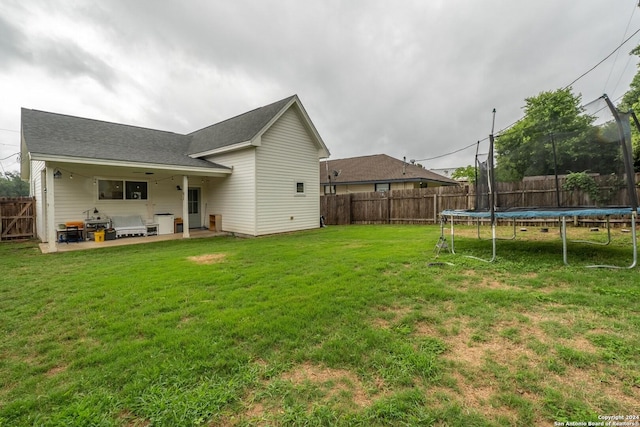 back of house featuring a lawn, outdoor lounge area, a trampoline, and a patio