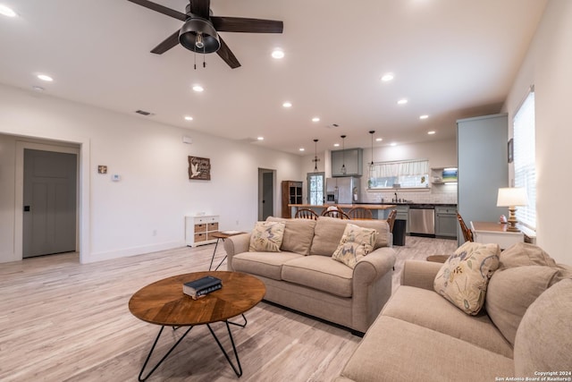 living room featuring ceiling fan, sink, and light hardwood / wood-style floors