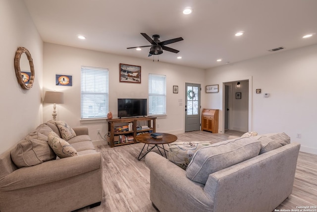 living room featuring light hardwood / wood-style floors, ceiling fan, and a healthy amount of sunlight