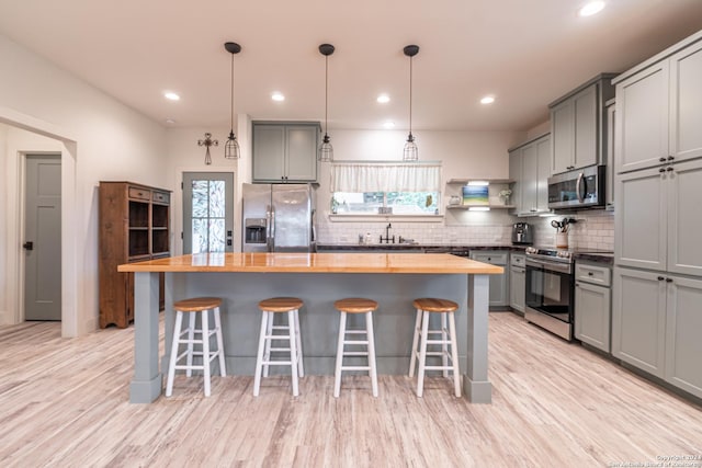 kitchen with a breakfast bar, a center island, stainless steel appliances, and wood counters