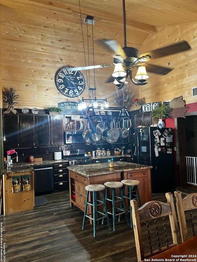 kitchen featuring wood ceiling, a kitchen island, a kitchen bar, ceiling fan, and dark stone counters