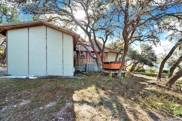 view of outdoor structure featuring cooling unit and a hot tub