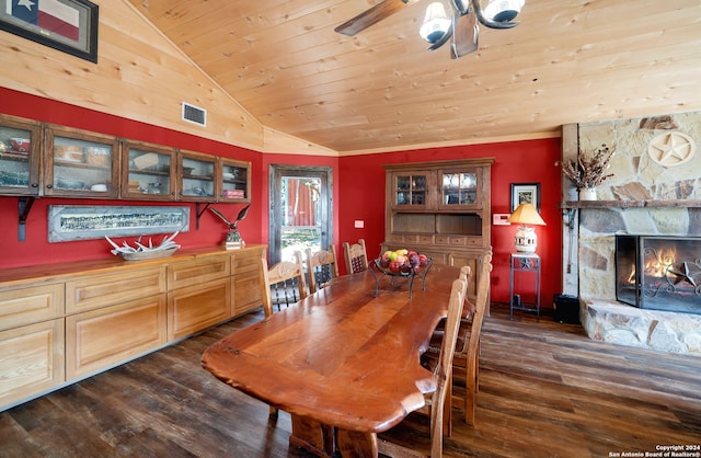 dining area featuring vaulted ceiling, a fireplace, ceiling fan, wood ceiling, and dark wood-type flooring