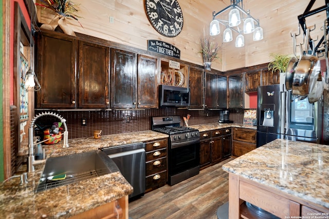 kitchen featuring dark brown cabinetry, sink, appliances with stainless steel finishes, pendant lighting, and light stone countertops