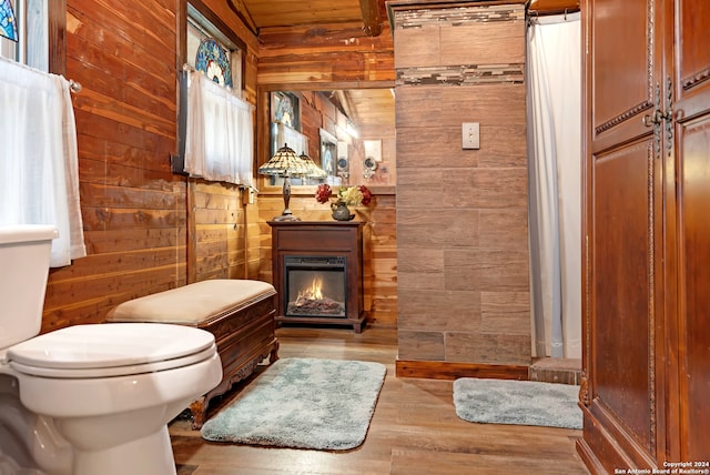 bathroom featuring wood-type flooring, wooden walls, and toilet