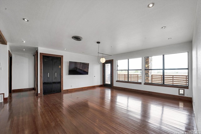 unfurnished living room featuring dark hardwood / wood-style floors and a textured ceiling