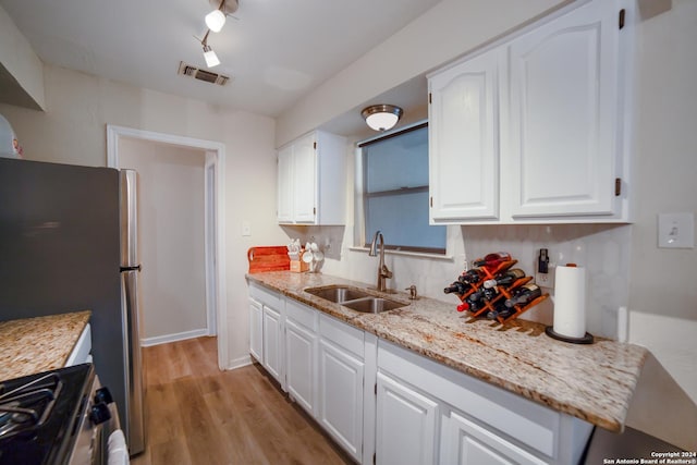 kitchen with white cabinetry, sink, stainless steel appliances, and light hardwood / wood-style floors