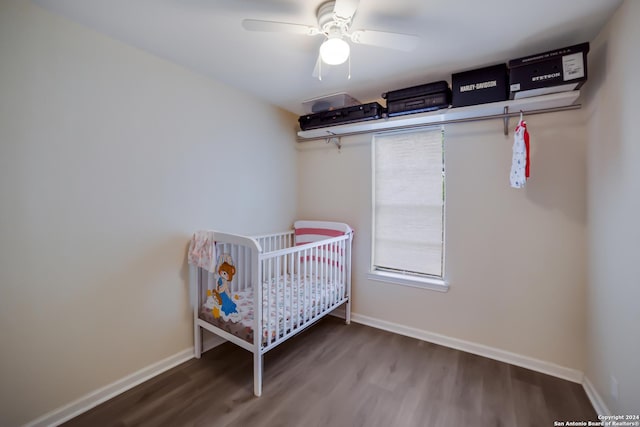 bedroom with hardwood / wood-style flooring, ceiling fan, and a crib