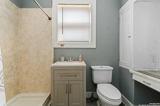 bathroom featuring a tile shower, vanity, and toilet