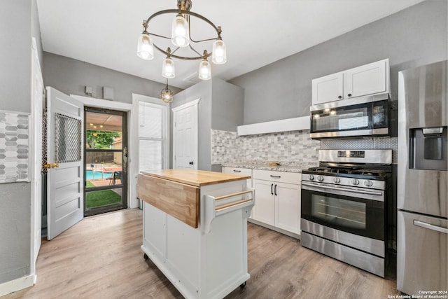 kitchen with white cabinets, hanging light fixtures, decorative backsplash, butcher block counters, and stainless steel appliances