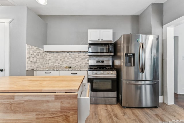 kitchen featuring wood counters, backsplash, appliances with stainless steel finishes, light hardwood / wood-style floors, and white cabinetry