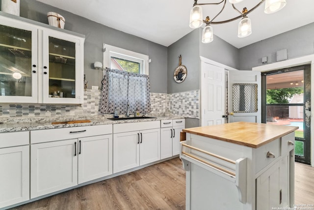 kitchen featuring backsplash, light stone counters, a chandelier, white cabinetry, and hanging light fixtures