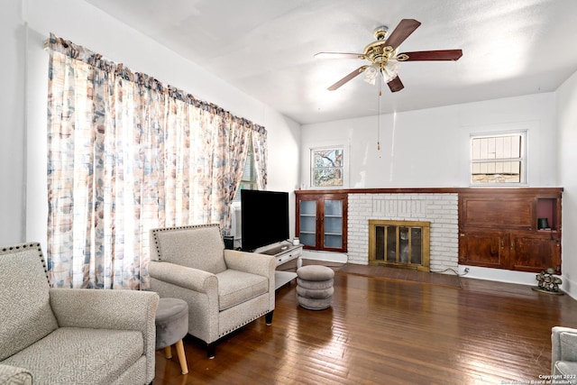 living room featuring a fireplace, ceiling fan, and dark wood-type flooring