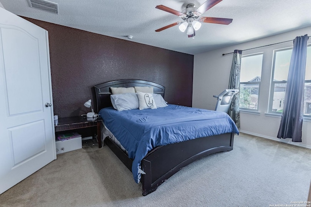 bedroom with a textured ceiling, carpet floors, and ceiling fan