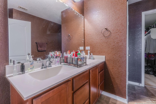 bathroom with a textured ceiling, vanity, and tile patterned flooring