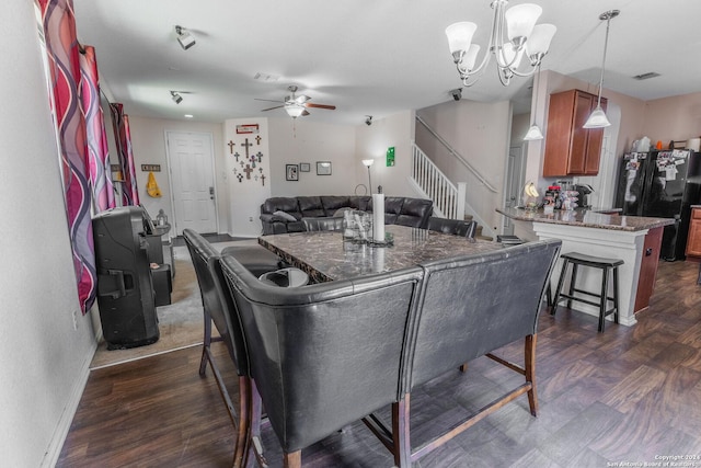 dining area with ceiling fan with notable chandelier and dark hardwood / wood-style flooring