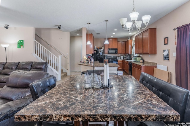 kitchen featuring kitchen peninsula, dark stone counters, a kitchen bar, black appliances, and an inviting chandelier