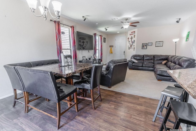 dining room with ceiling fan with notable chandelier and dark wood-type flooring