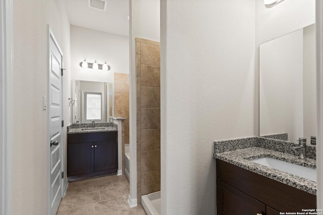 bathroom with tile patterned flooring, vanity, and walk in shower