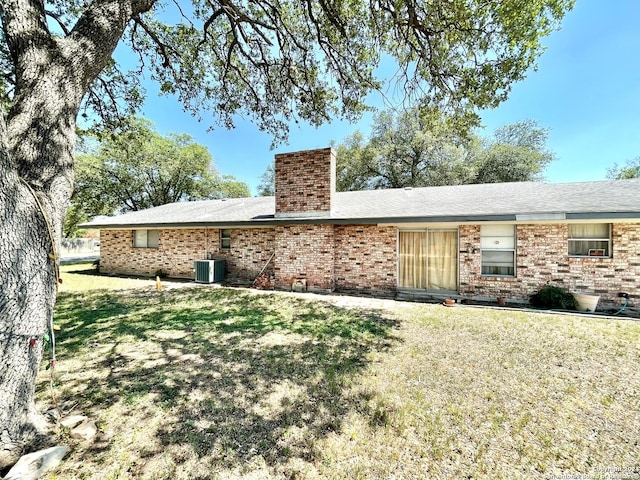 back of property with central air condition unit and a lawn