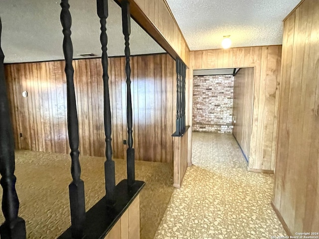 hallway with wood walls and a textured ceiling