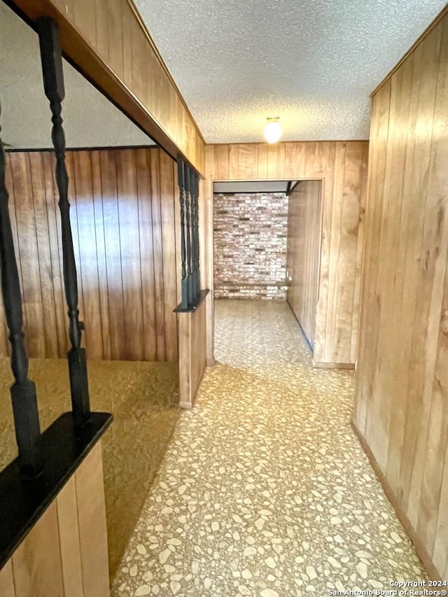 interior space featuring a textured ceiling and wood walls