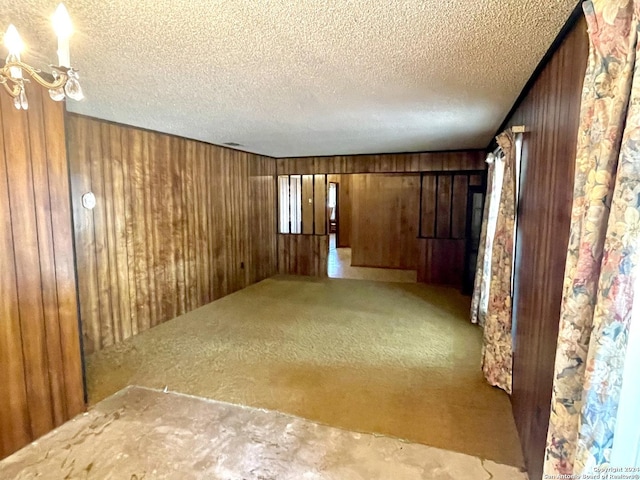 unfurnished room with carpet, a textured ceiling, and wooden walls