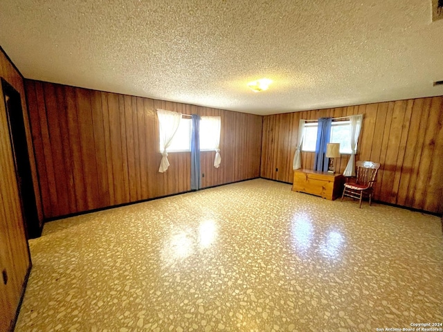 unfurnished room with a textured ceiling and wooden walls