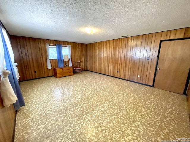 unfurnished bedroom with a textured ceiling and wooden walls