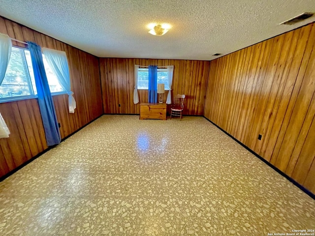 unfurnished room featuring wood walls and a textured ceiling