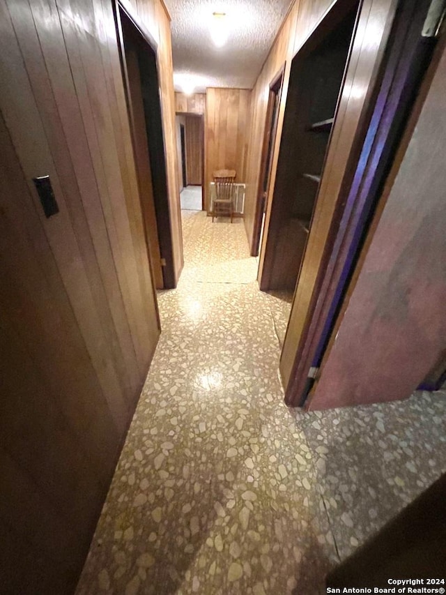 hallway featuring wood walls and a textured ceiling