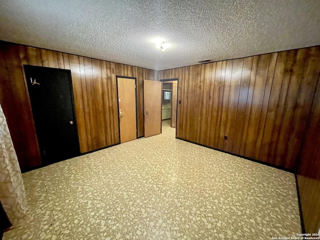 empty room with a textured ceiling and wooden walls