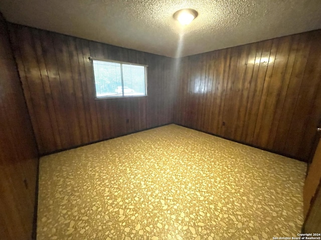 spare room featuring a textured ceiling and wooden walls