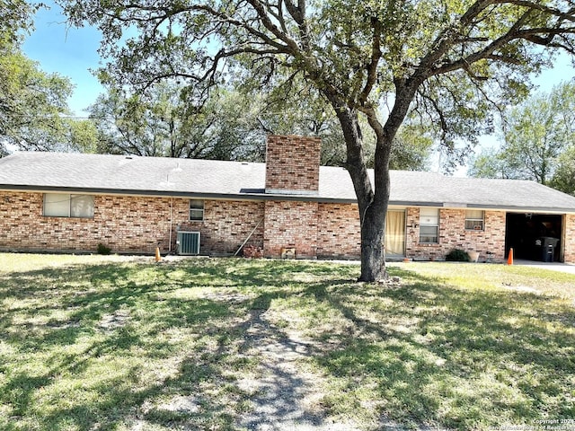 back of house featuring a garage, a yard, and cooling unit