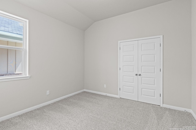 carpeted spare room with vaulted ceiling