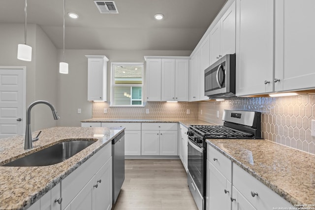 kitchen with light stone counters, sink, white cabinetry, and stainless steel appliances